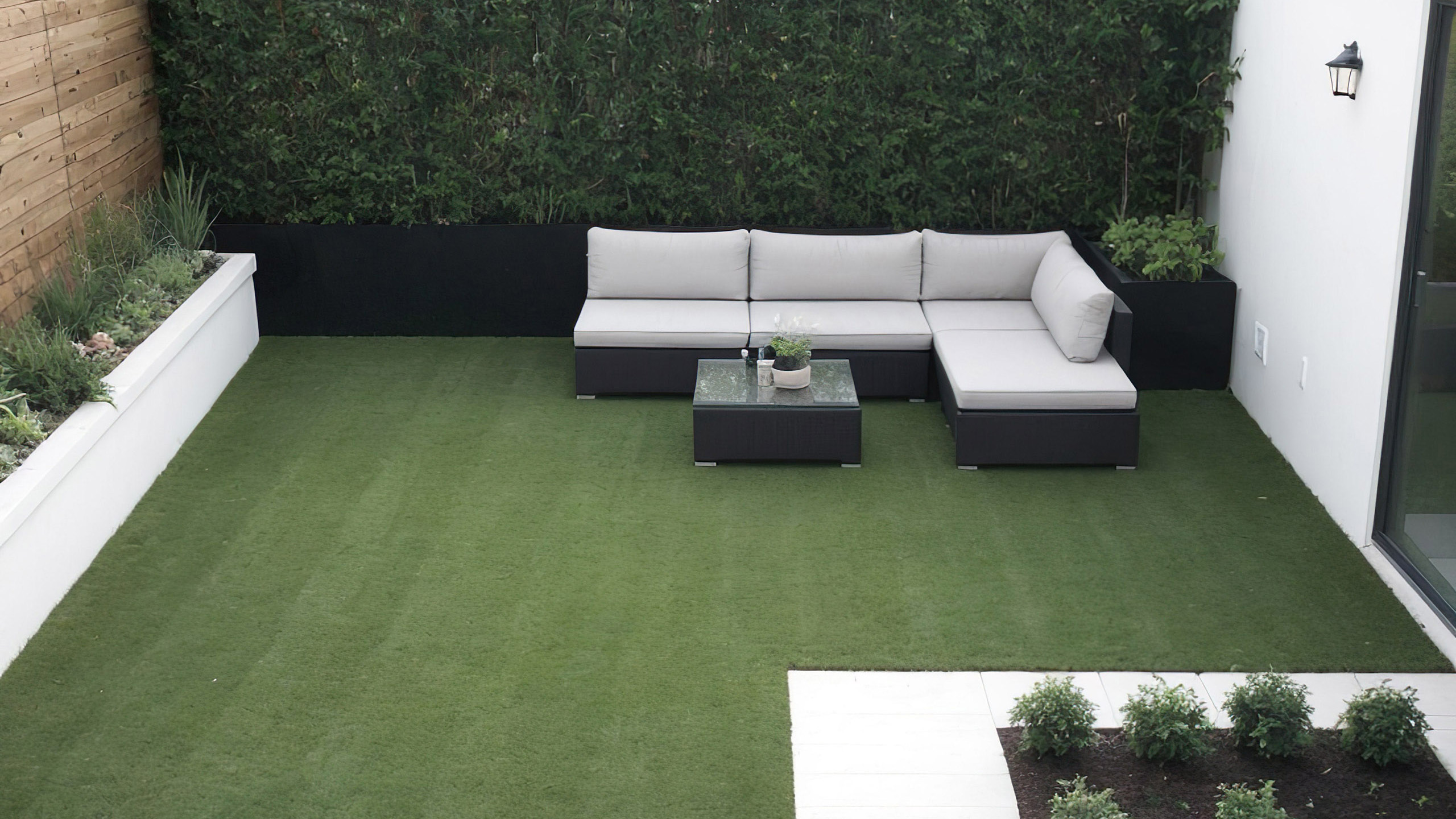 Modern backyard with green lawn and seating area.
